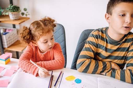 Little girls at home playing school with their brother