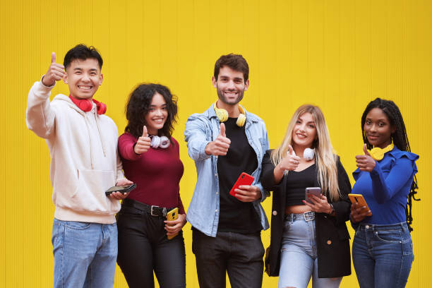 istock Multi-ethnic people showing thumbs up and smiling while standing against a yellow wall. 1502791013