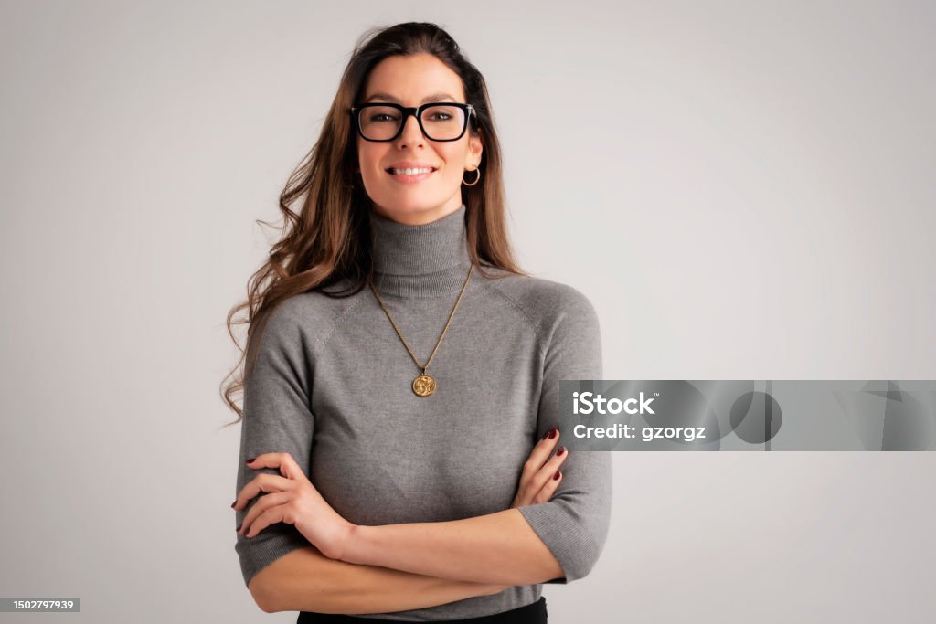 Portrait of an attractive brunette haired woman cheerful smiling against isolated background Attractive brunette haired woman standing with arms crossed at isolated background. Mid aged female wearing sweater and looking at camera. Copy space. Female wearing eyewear. Women Stock Photo Portrait of an attractive brunette haired woman cheerful smiling against isolated background Attractive brunette haired woman standing with arms crossed at isolated background. Mid aged female wearing sweater and looking at camera. Copy space. Female wearing eyewear. Women Stock Photo