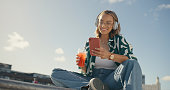 Young girl, headphones and cellphone in city with cool drink, mobile texting and social media app on mockup sky. Happy gen z woman, urban influencer and listening to music with smartphone outdoor