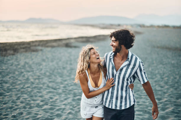 istock Cheerful couple having fun while walking embraced on the beach. 1502799947