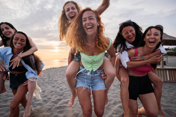 istock Female friends having fun while piggybacking on the beach 1502800406
