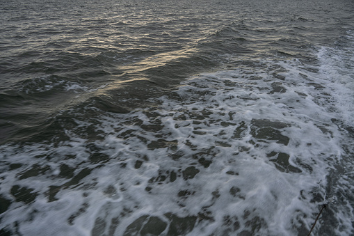 Seascape with turbulent dark blue water. In the sea before the storm, small waves with sea foam at the ends are already appearing