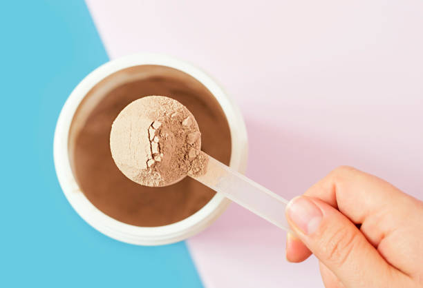 istock Chocolate protein powder in scoop and plastic jar on blue and pink background. 1502802378