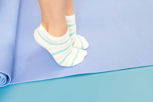 Female legs doing exercises lifting on toes close-up on blue background. stock photo