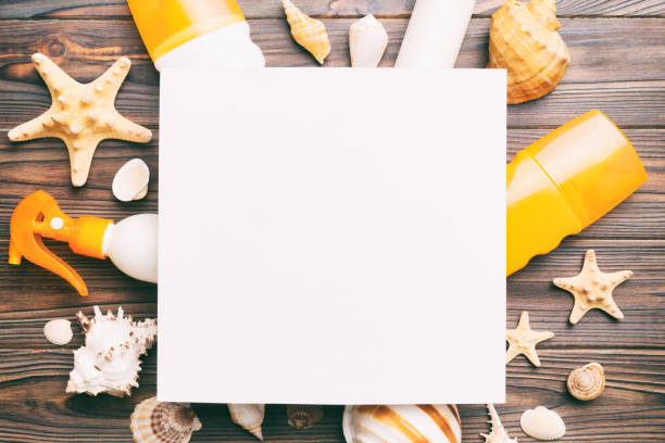 istock Summer time concept with blank greeting card and blank white paper on colored background. Seashells from ocean shore in the shape of frame separated with space for text top view 1502817732