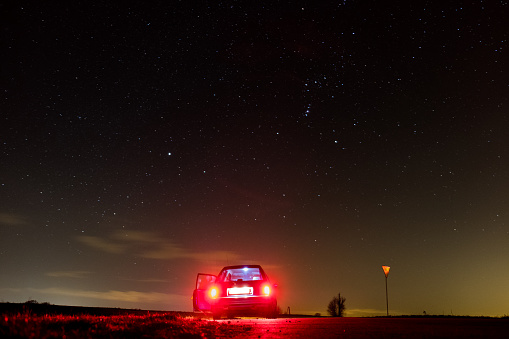Car on the background of the stars with the night sky, shining galaxy, red car taillights