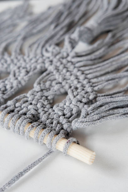 istock Close-up of handmade gray macrame texture pattern on white background. Eco-friendly modern concept of DIY knitting natural decor in the interior. Women's hobby. 1502822034