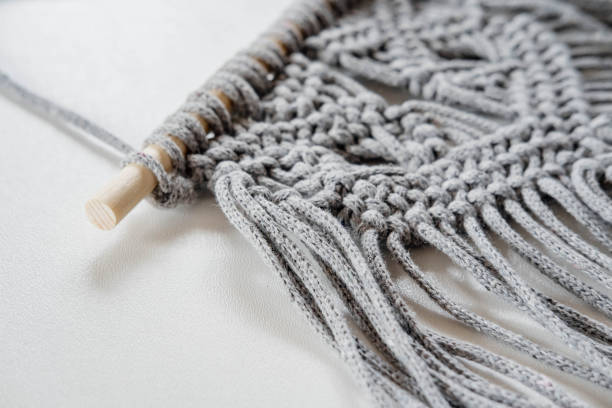 istock Close-up of handmade gray macrame texture pattern on white background. Eco-friendly modern concept of DIY knitting natural decor in the interior. Women's hobby. 1502822035