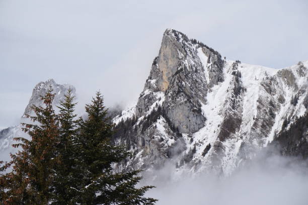 istock High pointed snow-capped mountain peeking through the clouds 1502822048