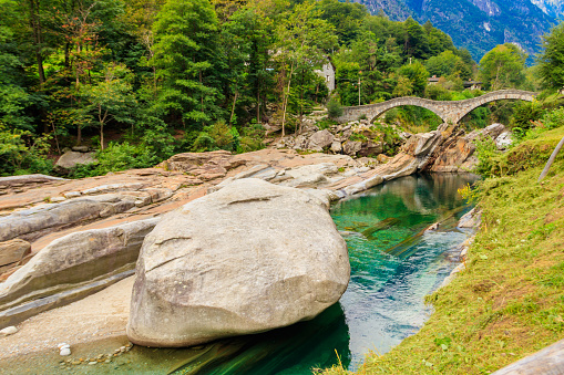 Ancient double arch stone Roman bridge (Ponte dei Salti) over the clear water of the Verzasca river in Lavertezzo ,Verzasca Valley, Ticino Canton, Switzerland