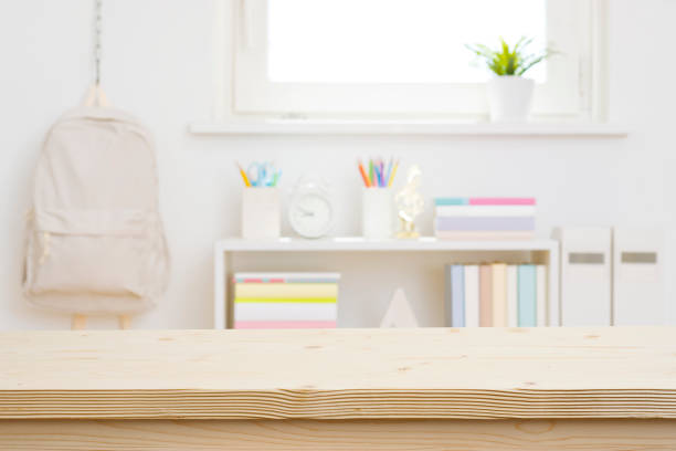 Blank wooden table top on blurred schoolchild room interior background