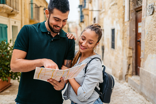 Beautiful young tourist couple reading a map in Valletta Malta.