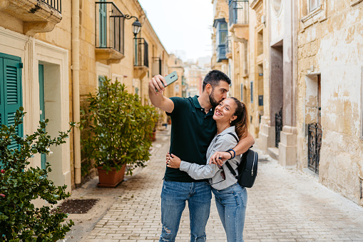 Beautiful young couple taking selfies on the street in Valletta Malta.