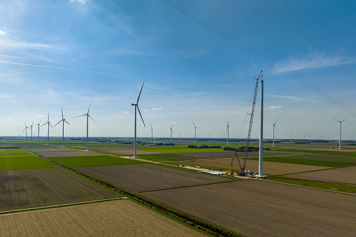 Wind turbine construction with huge cranes at a new wind park in Flevoland, Netherlands. Aerial view drone photo from above.