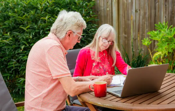 Photo of Senior couple checking finances outdoors in garden