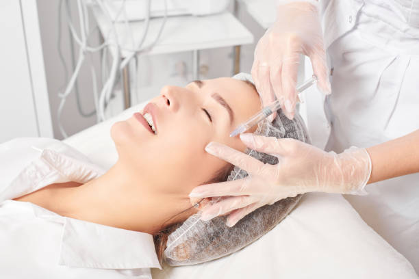 Cosmetologist makes rejuvenation injection in woman face, anti aging procedure in beauty salon stock photo