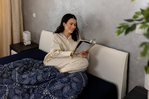 istock A beautiful young woman in a bed is relaxing while reading a book. 1502844959