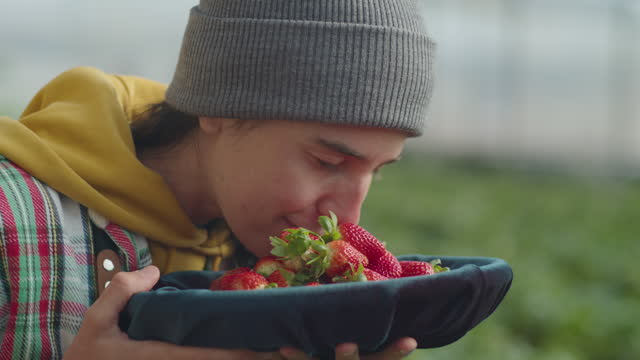 Young Female Farmer Enjoying Smell of Fresh Strawberry