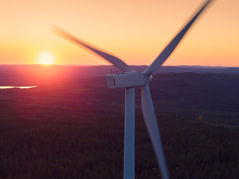 A wind turbine in a forest landscape at sunset in Dalarna, Sweden.