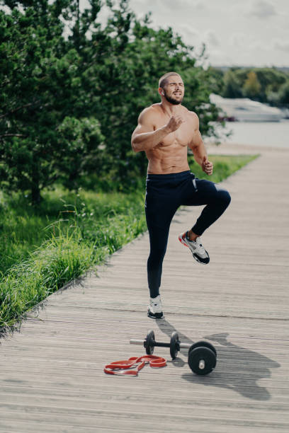 istock Fit bearded man warms up outdoors, does high knee tap exercise, prepares for running. Cardio training, strong body, determined mindset. 1502848449