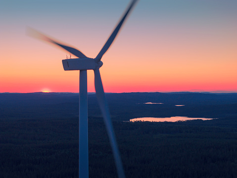 A wind turbine in a nature landscape with lakes at sunset in Dalarna, Sweden.
