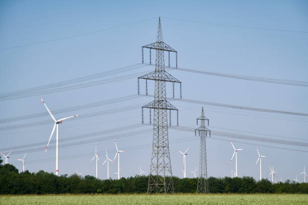 istock Two electricity pylons and wind turbines 1502853616