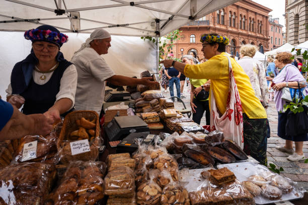 Riga, Latvia - June 22, 2023: The traditional summer solstice herb market in the Dome Square in the Old Town Riga. The salesman is selling bread