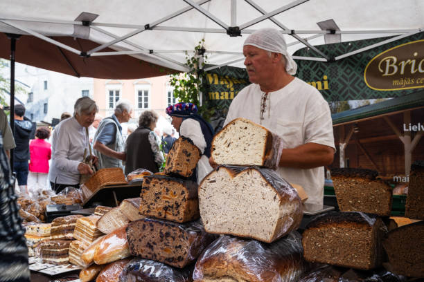 Riga, Latvia - June 22, 2023: The traditional summer solstice herb market in the Dome Square in the Old Town Riga. The salesman is selling bread
