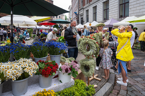 Riga, Latvia - June 22, 2023: The traditional summer solstice herb market in the Dome Square in the Old Town Riga. Various bouqets of flowers and different herbs are sold there. Tourists can be seen browsing the selection