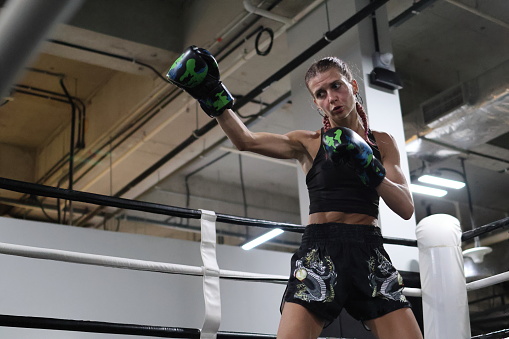 Young blonde woman at Thai boxing training in the ring