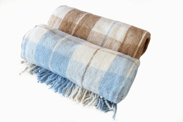 istock Woolen checkered plaid blanket isolated on a white background. Beige-brown and white-blue rolled blanket. Close up. 1502856985