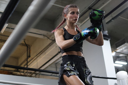 Young blonde woman at Thai boxing training in the ring