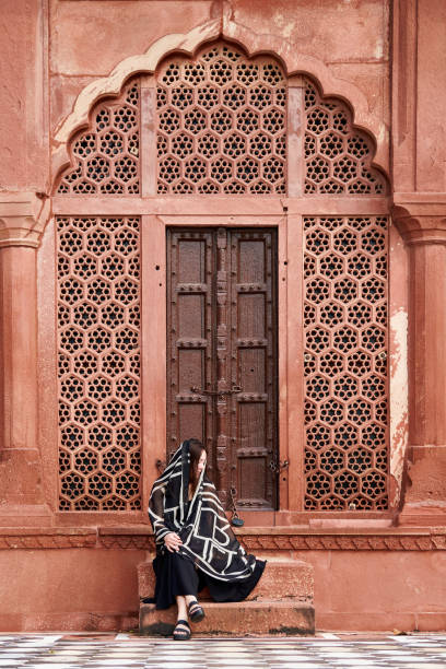 donna dell'asia orientale in vestito nero che si siede sui gradini dell'ingresso al tempio indiano - taj mahal mahal door temple foto e immagini stock