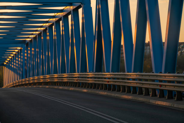 Asphalt road running over a truss bridge at sunset
