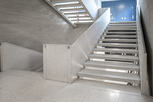 Concrete stairs in the hallway of an empty public access building. Modern architecture, bright interior space, no people.