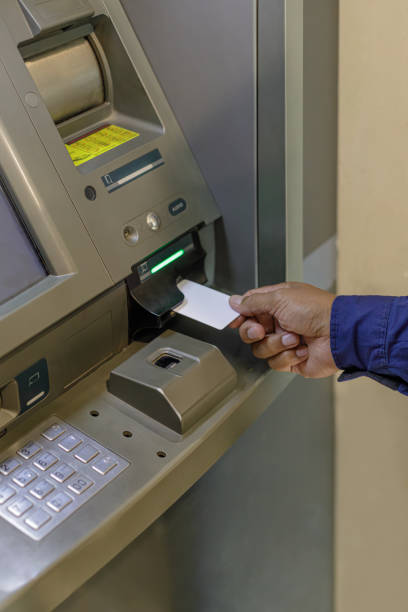 Detail of a man's hand inserting a blank card into an ATM.