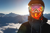 Portrait of a woman in the Alps. A young woman, a snowboarder or a skier in a snowy winter on a mountain slope, her beautiful happy eyes are visible through a ski mask or goggles