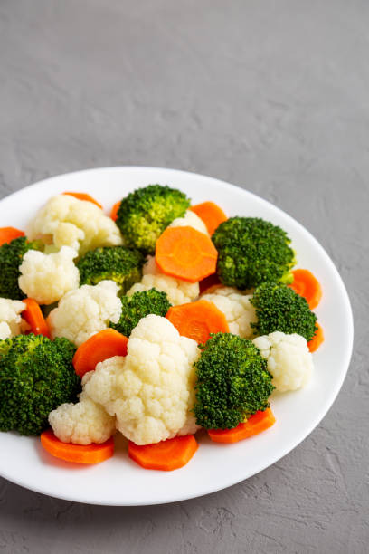 istock Mixed Organic Steamed Vegetables (Carrots, Broccoli and Cauliflower) on a Plate on a gray surface, side view. Copy space. 1502871492