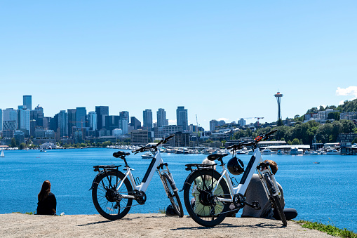 Seattle, WA, USA-July 2022; Panoramic view of the city and Union Lake from Kite Hill in Gas Works Park with in front some people relaxing in the grass with bicycles parked in front