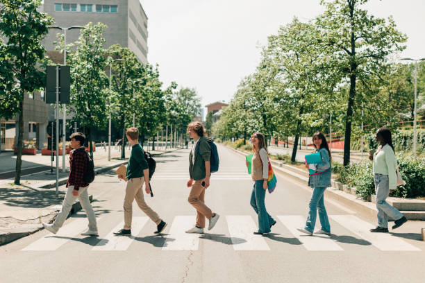 los estudiantes en una sola fila cruzan la calle en pasos de peatones como en abbey road - abbey road fotografías e imágenes de stock