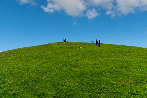 Seattle, WA, USA-July 2022; Low angle view of the grass on Kite Hill in Gas Works Park with some people on top of the hill with children letting up kites