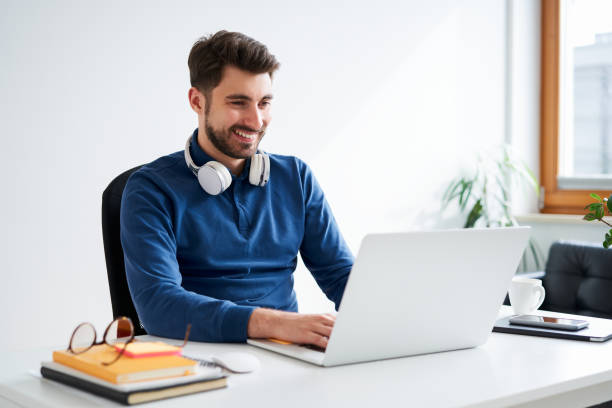 istock Happy young man working on laptop doing freelance job from home 1502875041
