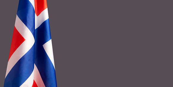 A Close-up of the Norway flag is on the left side on a gray background with copy space for text
