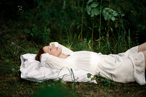 Healthy sound sleep. Rest, relaxation in the forest. Woman sleeps on a pillow on a green glade in the forest.