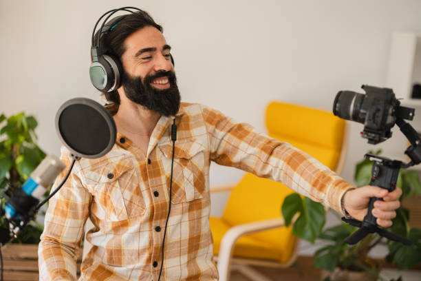 istock bearded middle-aged man recording video tutorial at home with headphones and photo camera. He is doing blogs for social media, influencer. 1502877516
