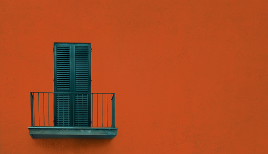 latticed wooden balcony with closed shutters on orange ginger color wall with copy space