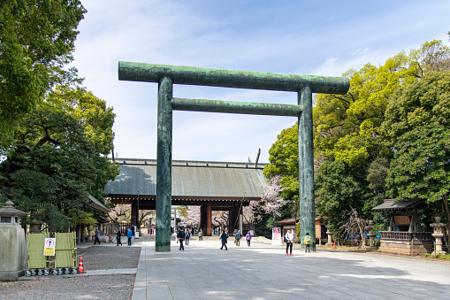 Tokyo, Japan-April 2023; View down footpath with Daini Torii (Second Shinto Shrine Arch), the biggest bronze torii gate in Japan leading to Shinto-style Yasukuni shrine commemorating Japanese war dead