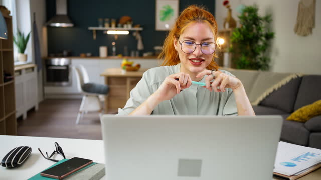 Redhead female freelancer with vitiligo and acne on her face, having a video call while working from home