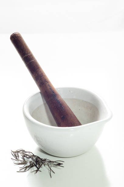 White and wooden ceramic pestle ideal for grinding nuts, herbs and spices maintaining the fibers, flavors and aromas of food, on a white background with selective focus